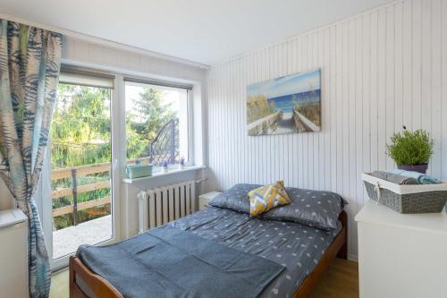 um quarto com uma cama e uma grande janela em Gniazdo. Apartamenty, pokoje em Jastrzębia Góra