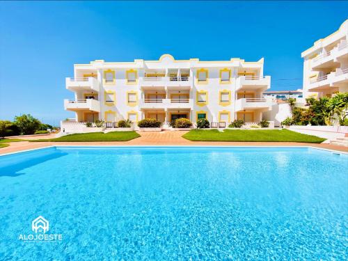 a villa with a swimming pool in front of a building at Água à Vista - Apto com 2 quartos e Piscina in Ericeira