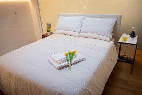 a white bed with towels and flowers on it at Mori Siciliani House in Aci Castello