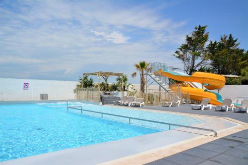 une piscine avec un toboggan et un toboggan dans l'établissement CAMP'HOTEL LE THAO LA ROCHELLE-ILE DE RE, à LʼHoumeau