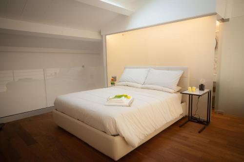 Un dormitorio con una gran cama blanca y una mesa en Mori Siciliani House en Aci Castello