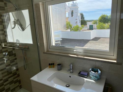 un bagno con un lavandino, uno specchio e una finestra di Casa Bravo a Querença