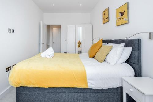 um quarto com uma cama grande com lençóis e almofadas amarelos em Deluxe 2 Bedroom St Albans Apartment - Free WiFi em Saint Albans