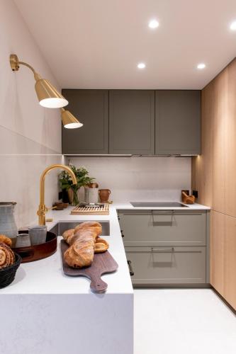 a kitchen with gray cabinets and a sink with a loaf of bread at Brunnenhof Luxury Apartments in Lech am Arlberg