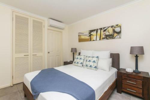 a bedroom with a large white bed and a night stand at Inner City One Bedroom Apartment 27 in Cairns