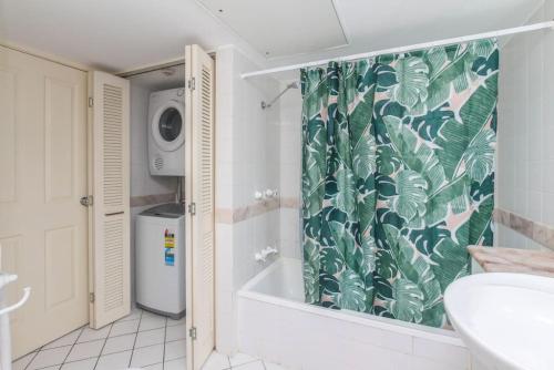 a bathroom with a shower curtain with a washing machine at Inner City One Bedroom Apartment 27 in Cairns