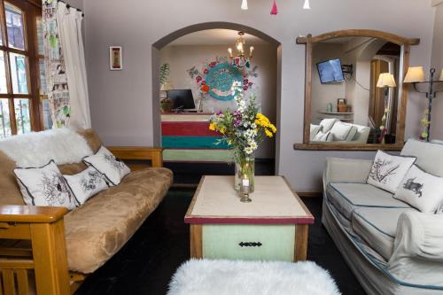 a living room with a couch and a table with flowers at La Justina Hostel in San Carlos de Bariloche
