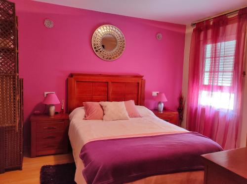 a bedroom with pink walls and a large bed with pink sheets at A Casiña do Patio in Quiroga
