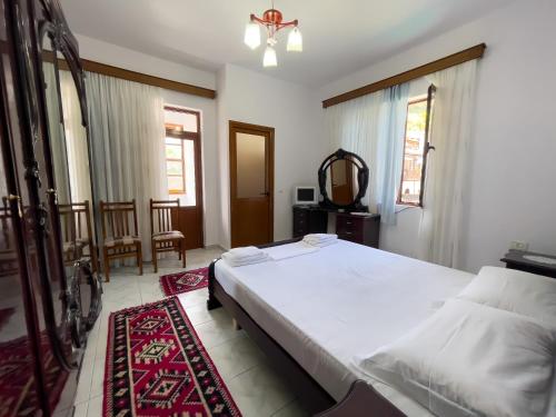 een slaapkamer met een groot wit bed en een spiegel bij White Villa in Berat