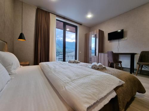 a bedroom with a large bed with a large window at Hotel Sweet Night in Kazbegi
