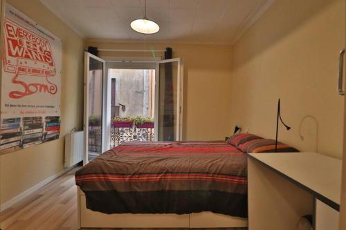 une chambre avec un lit et une grande fenêtre dans l'établissement Le Malbec - Maison de ville Beziers centre - Wifi, à Béziers