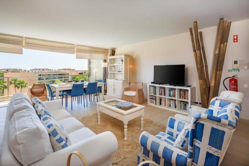 a living room with a couch and chairs and a tv at Salgados Vila das Lagoas in Albufeira