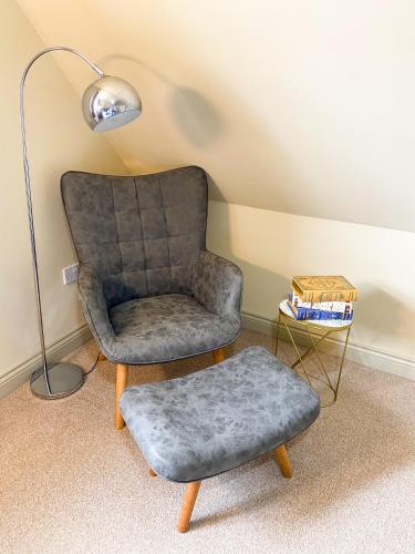 a chair and a ottoman in a room with a lamp at Kings Quarters Boutique Rooms in Hartford