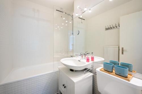 Baño blanco con lavabo y bañera en Casa Curnera 8 en Laax