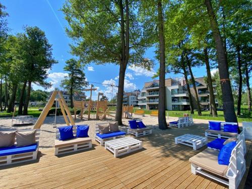 eine Terrasse mit blauen und weißen Liegestühlen und Bäumen in der Unterkunft Nautica Resort in Giżycko