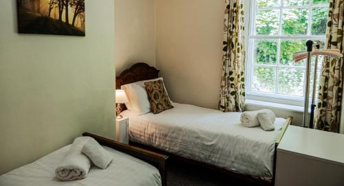 a small room with two beds and a window at Painter's Cottage in Matlock Bank