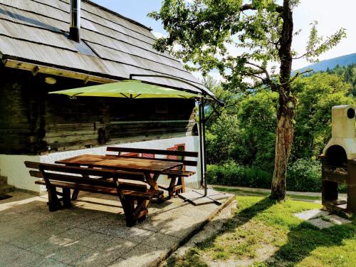a picnic table with an umbrella next to a building at Natur pur Pikovo in Črna na Koroškem