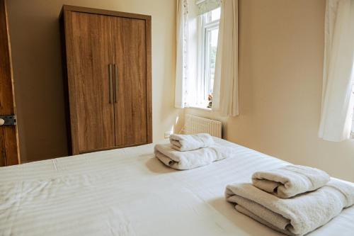 a bedroom with two towels sitting on a bed at Painter's Cottage in Matlock Bank