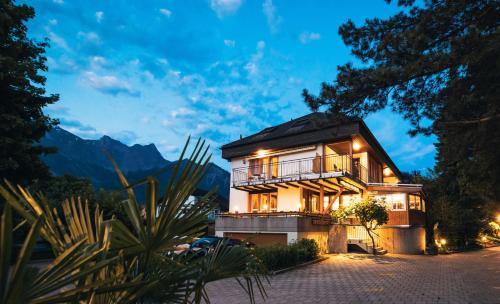 a house with a balcony at night with mountains at Garni Hotel Torkelbündte in Bad Ragaz