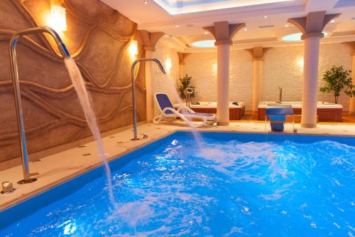 uma piscina num quarto de hotel com uma banheira de hidromassagem em Hotel Adam & Spa em Kudowa-Zdrój