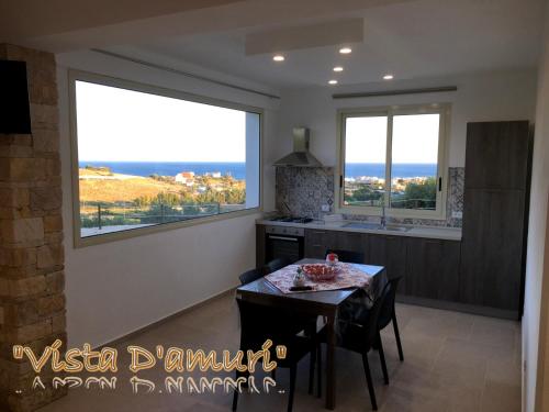 a dining room with a table and two windows at VISTA D'AMURI in Sciacca
