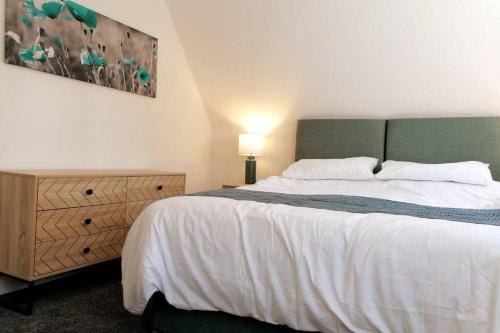 a bedroom with a large white bed and a dresser at Clement's Retreat on the North Norfolk Coast in Cromer
