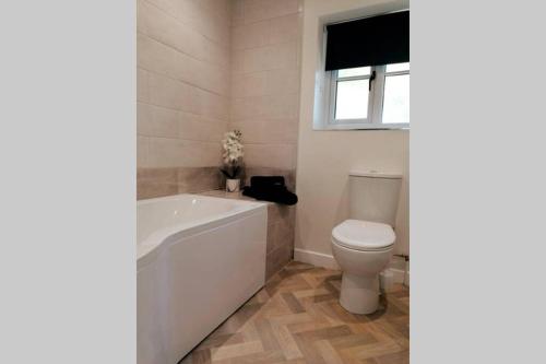 a bathroom with a tub and a toilet and a window at Clement's Retreat on the North Norfolk Coast in Cromer