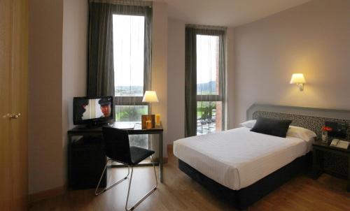 a bedroom with a bed and a chair and windows at Ciutat de Granollers in Granollers