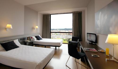 a hotel room with two beds and a desk at Ciutat de Granollers in Granollers