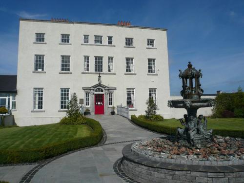 a white building with a red door and a fountain at New Forest Estate Lodges in Tyrrellspass