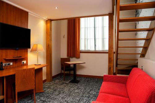 a hotel room with a red couch and a desk at Best Western Plus Hôtel Colbert in Châteauroux
