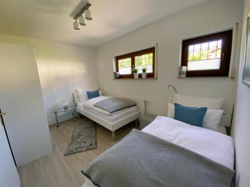 a bedroom with two beds and a table and two windows at Odenwald Chalet in Erbach im Odenwald