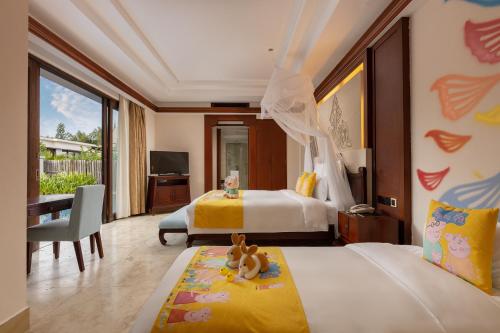 a bedroom with two beds and a desk and a television at Pullman Sanya Yalong Bay Villas & Resort in Sanya
