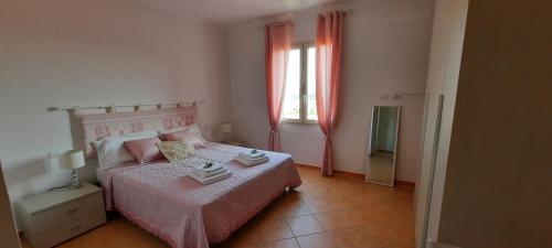 a bedroom with a pink bed and a window at Monte Becco panoramic rooms in Santa Teresa Gallura