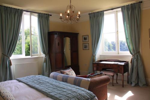 a bedroom with a bed and a desk and windows at The Manor House Bed and Breakfast in Castle Acre