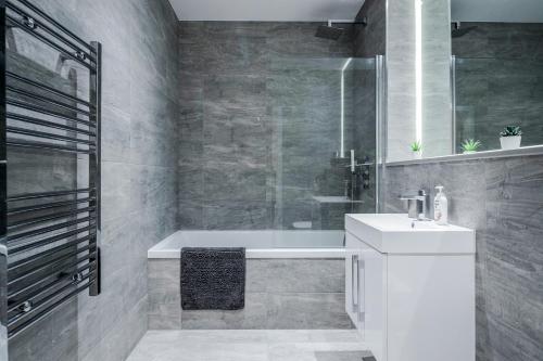 uma casa de banho com um lavatório branco e uma banheira em Deluxe 1 Bedroom St Albans Apartment - Free Wifi em Saint Albans