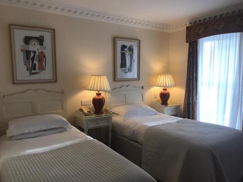 two beds in a bedroom with two lamps and a window at Foley's Townhouse Killarney in Killarney