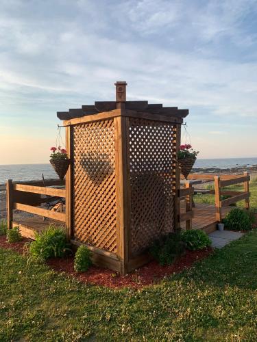 a wooden out house with flowers on a fence at Les studios de la mer in Matane