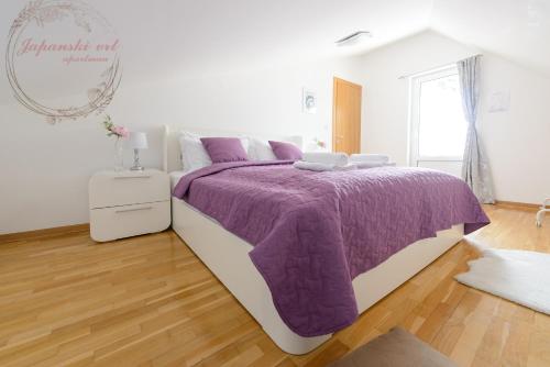 a bedroom with a bed with a purple blanket at Apartman Japanski vrt, Centar in Vrnjačka Banja