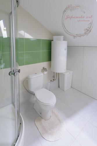 a white bathroom with a toilet and a shower at Apartman Japanski vrt, Centar in Vrnjačka Banja