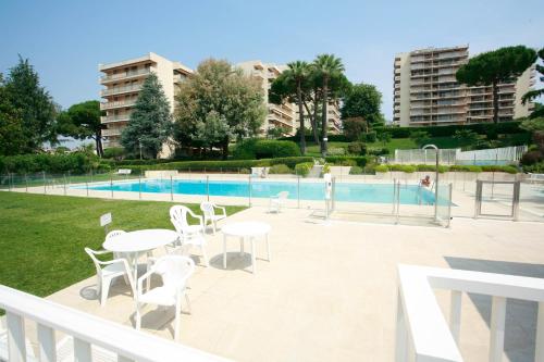 un patio avec tables et chaises à côté d'une piscine dans l'établissement Le Tamaris - Terrasse Vue sur Mer - Piscine, Tennis & Jardin, à Antibes
