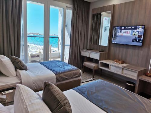 Jewel Beach Matrouh Hotel في مرسى مطروح: غرفة فندقية بسريرين وتلفزيون بشاشة مسطحة