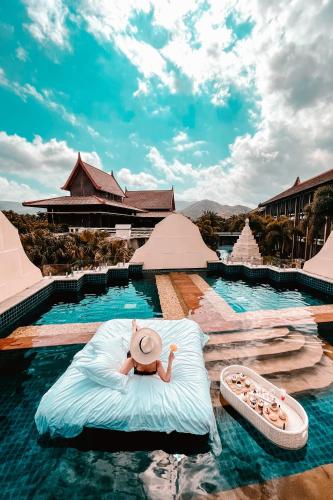 a person laying on a bed in the water at a resort at Pullman Sanya Yalong Bay Villas & Resort in Sanya