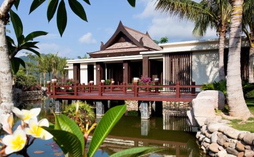 a resort with a bridge over a pond and palm trees at Pullman Sanya Yalong Bay Villas & Resort in Sanya