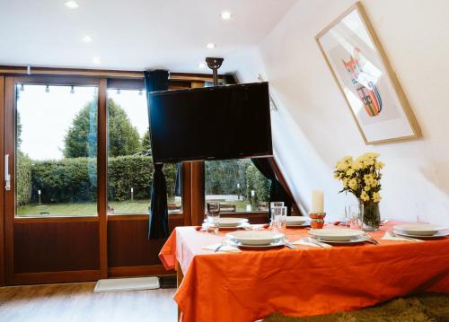 a dining room with a table with a television on the wall at Nurdachhaus Marie im Nordschwarzwald in Neuhausen