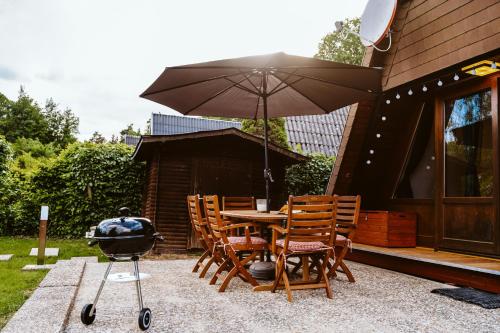 a patio with a table and chairs and an umbrella at Nurdachhaus Marie im Nordschwarzwald in Neuhausen