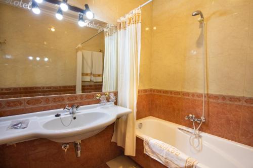 a bathroom with a sink and a bath tub at Hotel Hidalgo in Martos