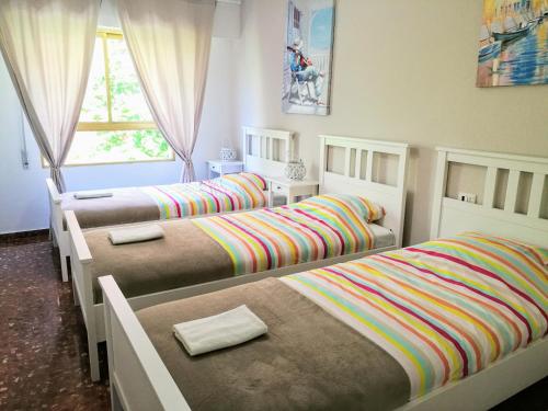 a bedroom with three beds and a window at Apartamento Tibi - centro de Gandia in Gandía