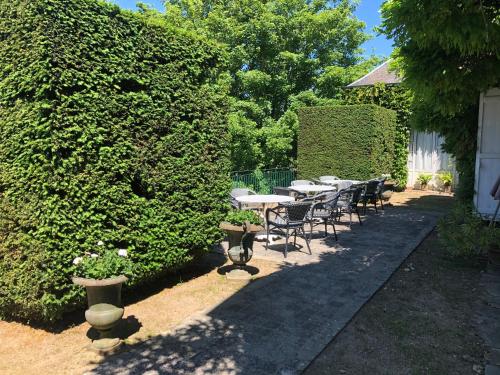 a row of tables and chairs in a garden at Hotel La Croix De Vernuche in Varennes Vauzelles