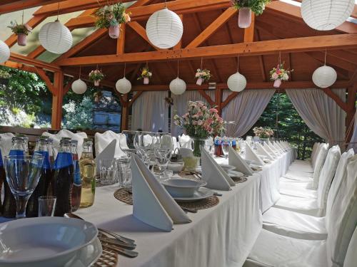 - une grande table avec des chaises blanches, des assiettes et des verres à vin dans l'établissement Hotel i Restauracja Pod Skałą Jasło, à Jasło